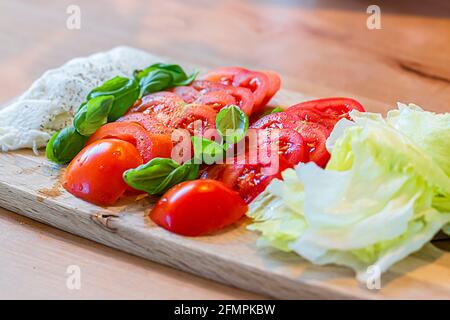 Des tomates en tranches avec de la mozzarella et du basilic se trouvent sur un bois carte Banque D'Images