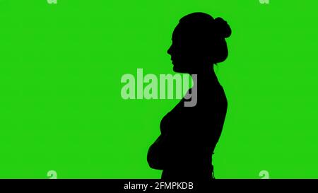 Silhouette de femme avec les bras croisés sur fond vert Banque D'Images