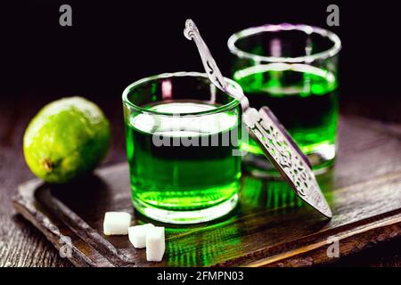 doses d'absinthe avec des cubes de sucre brun. distillat d'absinthe dans une cuillère en verre et citron, isolée sur fond noir Banque D'Images