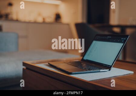 Ordinateur portable sur une table à l'intérieur d'un appartement, petit foyer sélectif, concept de travail à la maison. Banque D'Images