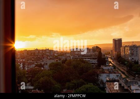 Un coucher de soleil calme incroyable dans une heure dorée au-dessus de la petite ville. Paysage urbain avec le soleil couchant au-dessus de l'horizon. Horizon urbain et toits après la pluie. Banque D'Images
