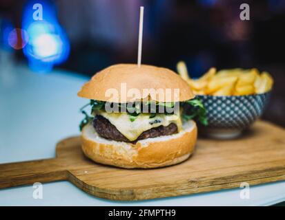 Cheeseburger gastronomique servi avec du pain maison et accompagné de français Frites Banque D'Images