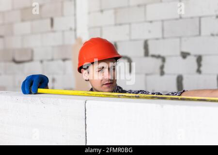 Les mesures de construction de jeune homme une partie nécessaire de l'aéré bloc de béton Banque D'Images