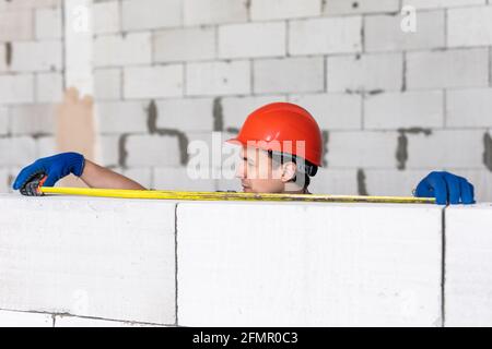 La couche de brique mesure un mur nouvellement construit avec un mètre ruban. Construction Banque D'Images