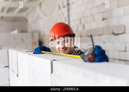 Les mesures de construction de jeune homme une partie nécessaire de l'aéré bloc de béton Banque D'Images