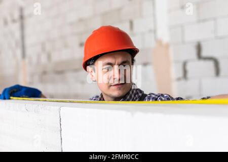 Les mesures de construction de jeune homme une partie nécessaire de l'aéré bloc de béton Banque D'Images