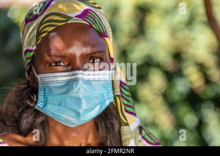 Femme africaine d'âge moyen, femme en Afrique, portant des vêtements traditionnels et un masque facial en cas de pandémie de coronavirus COVID-19 Banque D'Images
