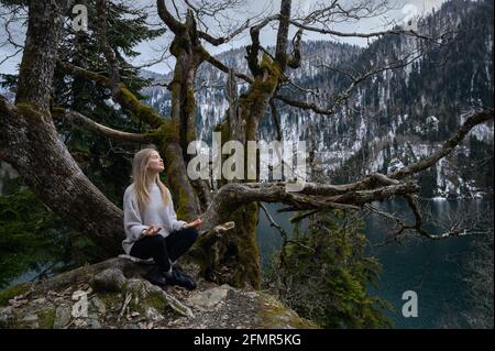 Elle est assise sur un arbre et médite près du lac Ritsa En Abkhazie Banque D'Images