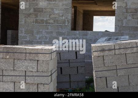 Construction d'une maison privée à partir de blocs de cendre. Lots de blocs gris sur palettes sur un chantier de construction. Banque D'Images