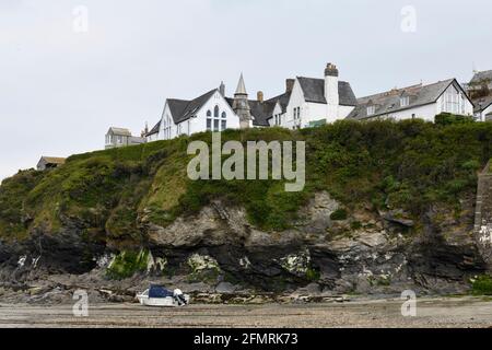 Port Issac avec bateau de plaisance sur les sables et The Old School on the Cliff top Cornwall Angleterre Royaume-Uni Banque D'Images