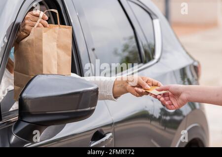 Les femmes échangeant une carte de crédit par une fenêtre de voiture Banque D'Images