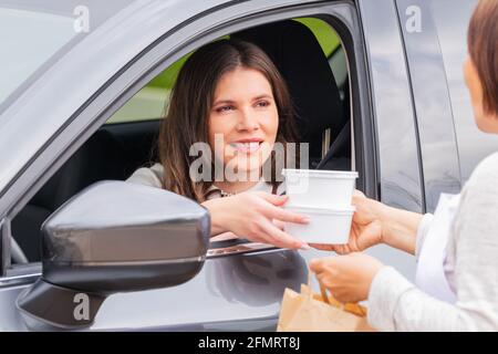 Femme dans une voiture saisissant des récipients de nourriture à emporter Banque D'Images