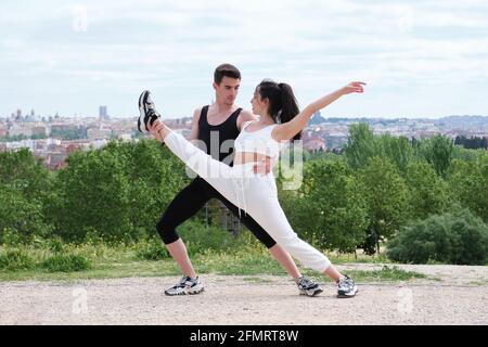 Jeune couple pratiquant la danse de rue, le ballet, les marches dansantes, les mouvements dans un parc. Banque D'Images