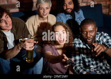 Groupe interracial d'amis discuter quel film à regarder, assis sur canapé à la maison, choisir le film le plus intéressant, les gens détendus ont parler, Swit Banque D'Images