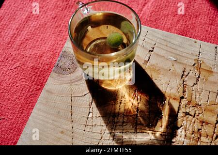 Tasse de thé de linden isolée en verre et il y a de la sueur et des bonbons vert mentholés. Pot en verre rempli de thé entièrement en linden existant sur une plaque en bois Banque D'Images