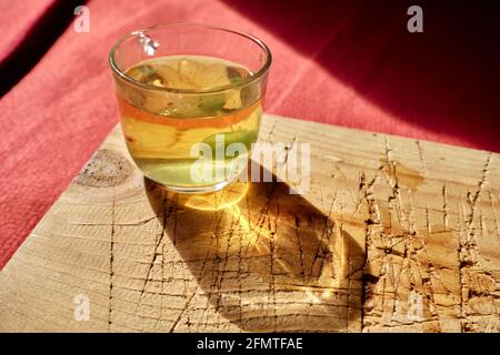 Tasse de thé de linden isolée en verre et il y a de la sueur et des bonbons vert mentholés. Pot en verre rempli de thé entièrement en linden existant sur une plaque en bois Banque D'Images