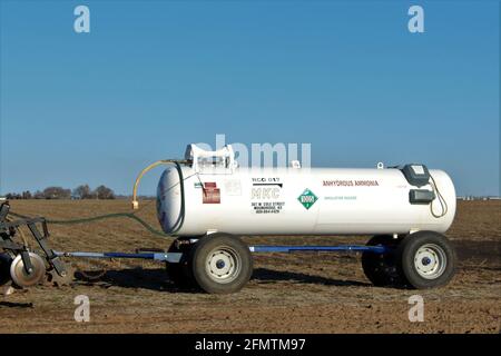 Le réservoir d'ammoniac anhydre MKC dans une ferme de gros plan accroché derrière un tracteur agricole lors d'une journée colorée au Kansas. Banque D'Images