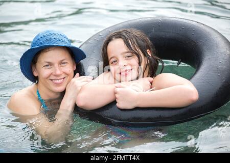 Portrait de la mère et de la fille de onze ans flottant dans la piscine Banque D'Images