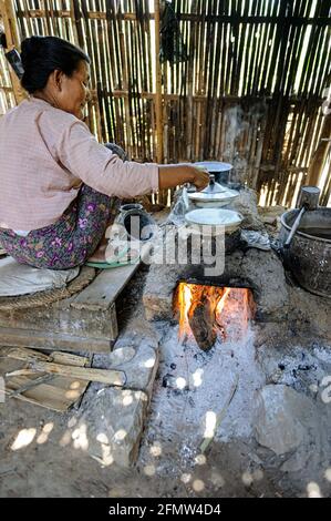 Femme cuisinant de la nourriture sur un poêle à bois primitif dans l'État de Shan, Myanmar Birmanie Banque D'Images