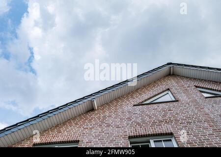 Angle bas d'une ancienne maison en briques, sous un ciel nuageux ciel Banque D'Images