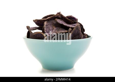Chips de pommes de terre à base de pommes de terre violettes dans un bol turquoise isolé sur fond blanc Banque D'Images