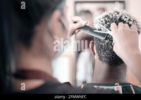 Coiffeur femme avec masque de protection travailler dans le salon de coiffure. Beauté, coiffure et concept de personnes. Banque D'Images