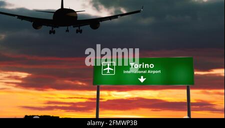 Silhouette d'avion atterrissage à Turin, Italie. Arrivée en ville avec panneau indiquant la direction de l'aéroport et coucher de soleil en arrière-plan. Concept de voyage et de transport Banque D'Images