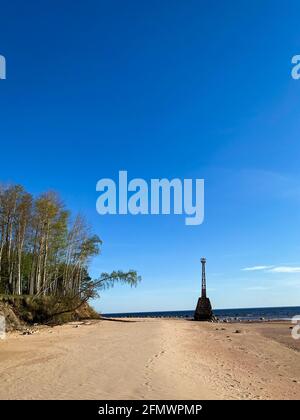 Belle plage de mer avec sable de dunes et un vieux phare abandonné. Le phare est basé sur de grandes pierres. Un gros bouleau se déforme du sandsto Banque D'Images