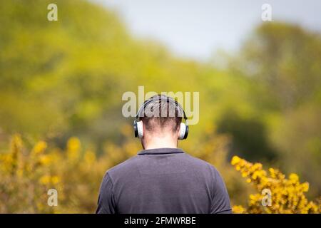 Vue arrière d'un homme portant un casque pendant qu'il marche dans la campagne Banque D'Images