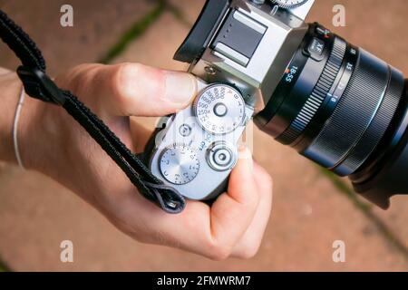 Gros plan d'un boîtier d'appareil photo sans miroir vintage avec objectif par une personne main avec la sangle Banque D'Images