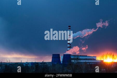 centrale thermique sur fond d'un coucher de soleil en soirée et d'un ciel bleu, la vapeur provient des tuyaux de la centrale. Espace de copie pour le texte, te Banque D'Images