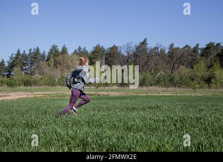 Jeune femme mince jogging dans la nature. Mode de vie actif. Entraînement pour des avantages pour la santé. Adolescente traversant la prairie Banque D'Images