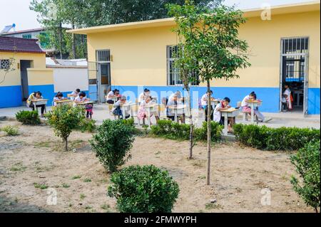 Élèves du primaire dans une école rurale à Qufu, Shandong, Chine social distanciant eux-mêmes pendant leur classe. Banque D'Images