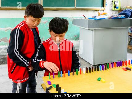 Élèves du primaire qui sont jumeaux jouant des dominos dans une école rurale de Qufu, Shandong, Chine. Banque D'Images