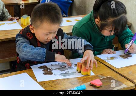 Les élèves de la maternelle dans une école rurale de Qufu ayant des cours d'art à leur bureau. Banque D'Images