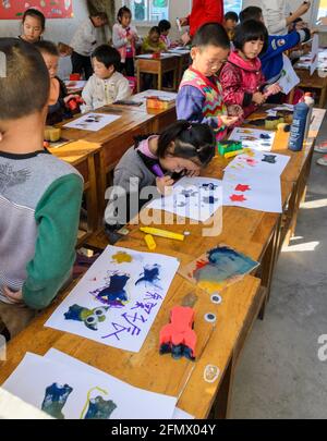 Les élèves de la maternelle dans une école rurale de Qufu ayant des cours d'art à leur bureau. Banque D'Images