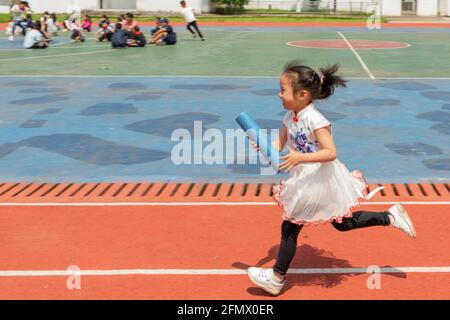 Des élèves de la maternelle de l'école primaire centrale de Weiqiao à Xiuning, Anhui, Chine participent à un concours de relais Banque D'Images