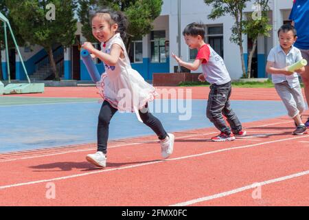 Des élèves de la maternelle de l'école primaire centrale de Weiqiao à Xiuning, Anhui, Chine participent à un concours de relais Banque D'Images