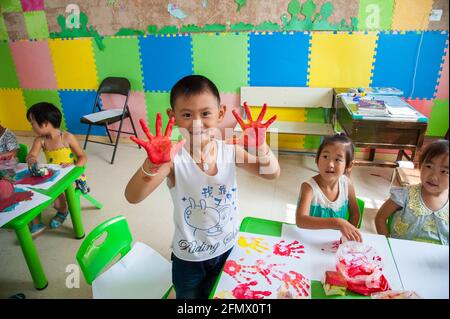 Des élèves de maternelle d'une école rurale du comté de Xiuning, à Anhui, en Chine, apprécient la classe de peinture de doigt. Banque D'Images