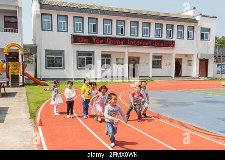 Des élèves de la maternelle de l'école primaire centrale de Weiqiao à Xiuning, Anhui, Chine participent à un concours de relais Banque D'Images