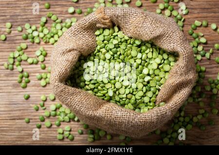 Diviser les petits pois séchés dans un sac sur fond de bois, vue de dessus Banque D'Images