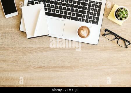 Composition minimaliste de dessus plats avec clavier noir et blanc pour ordinateur portable, gadget pour téléphone portable, tasse de café et lunettes pliées sur bureau en bois texturé Banque D'Images