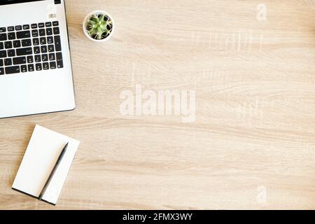 Gros plan composition: ordinateur portable clavier, page vierge ordinateur planificateur, stylo et plante de cactus sur table en bois avec motif de texture de bois visible. B Banque D'Images