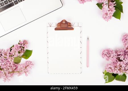 Ordinateur de bureau féminin gros plan d'ordinateur portable clavier, fleurs lilas. Composition de la pose à plat, bloc-notes, presse-papiers pour feuilles vierges, crayon, liste des tâches vide, Banque D'Images