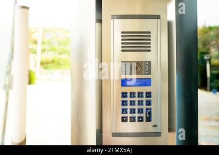 Gros plan du dispositif de code du système de sécurité avec boutons numérotés sur le dispositif d'interphone moderne avec écran LCD bleu près de la porte d'entrée. Verrouillage électronique à code Banque D'Images