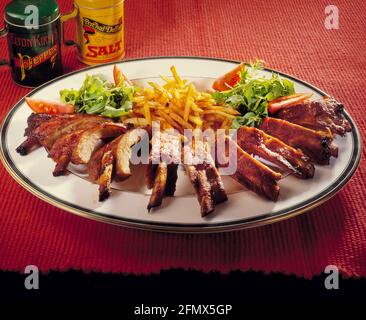 Cuisine de pub britannique, côtes de bœuf frites salade de tomates sur plaque blanche sur fond rouge noir au bas de l'espace de copie Banque D'Images