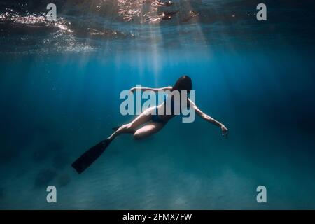 Belle femme de frediver avec nageoires plongée sous l'eau profonde dans la mer. Banque D'Images