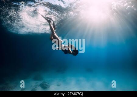 Belle femme de frediver avec nageoires plongée sous l'eau profonde dans la mer. Banque D'Images