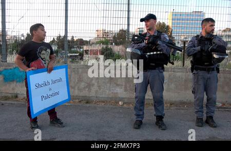 Un jeune palestinien tient un écriteau qui lit 'Cheikh Jarrah est Palestine' à côté de la police lors d'une manifestation contre l'expulsion de familles palestiniennes de leurs foyers et l'activité de peuplement dans Sheikh Jarrah, un quartier majoritairement palestinien, le 07 mai 2021, à Jérusalem-est, en Israël. Des dizaines de résidents palestiniens de Sheikh Jarrah ont été victimes d’évictions potentielles pendant des années, dans le cadre d’efforts intensifiés de la part de groupes de colons de droite qui affirment que la terre appartenait aux juifs avant 1948, date de la fondation d’Israël. La menace d'expulsion a conduit à de fréquentes manifestations. Banque D'Images