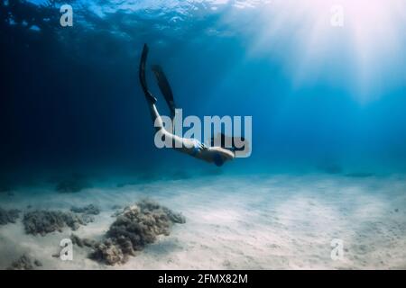 Belle femme de frediver avec nageoires plongée sous l'eau profonde dans la mer. Banque D'Images